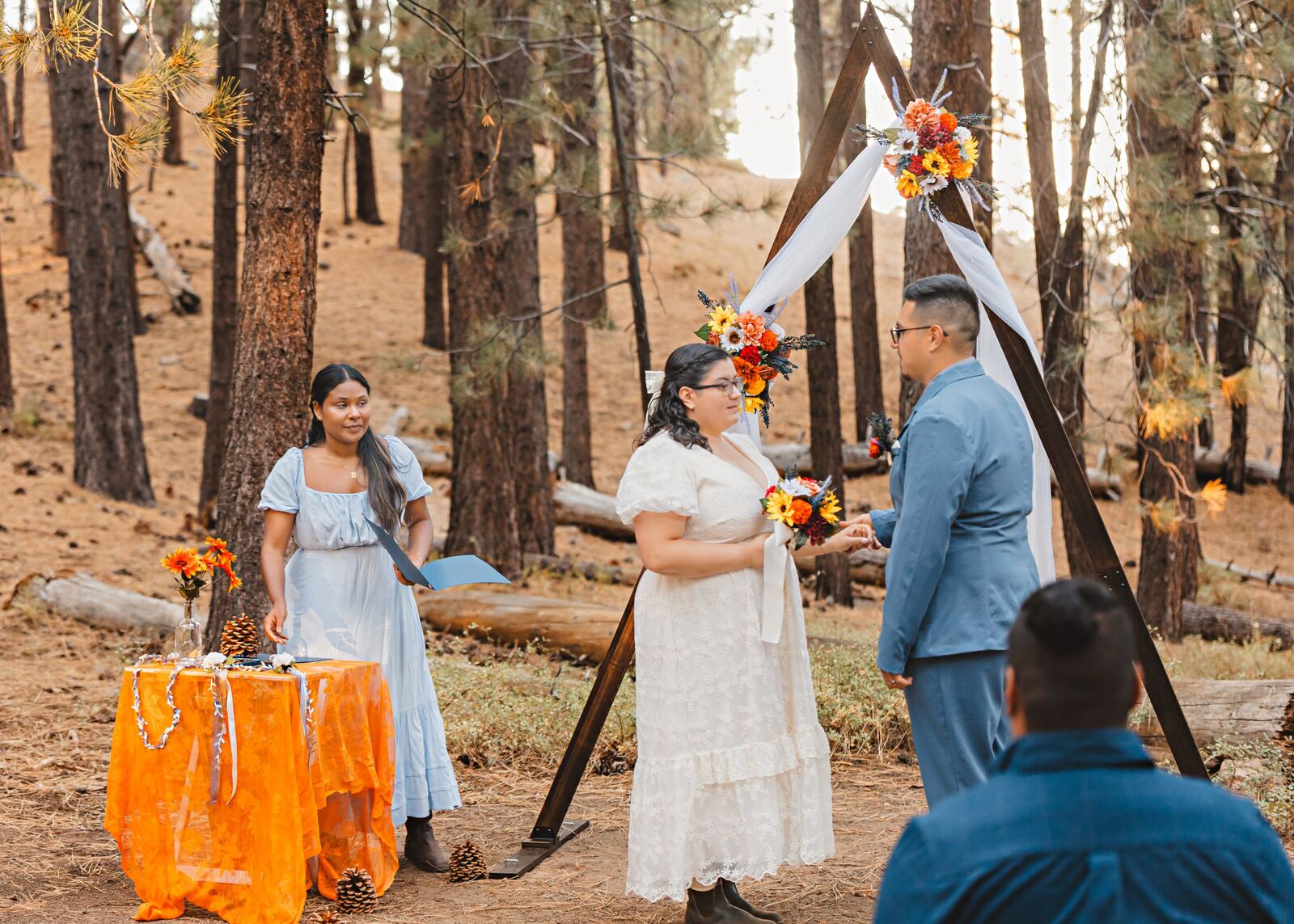 Andria officiating Estella and Derek's forest wedding ceremony under a floral arch