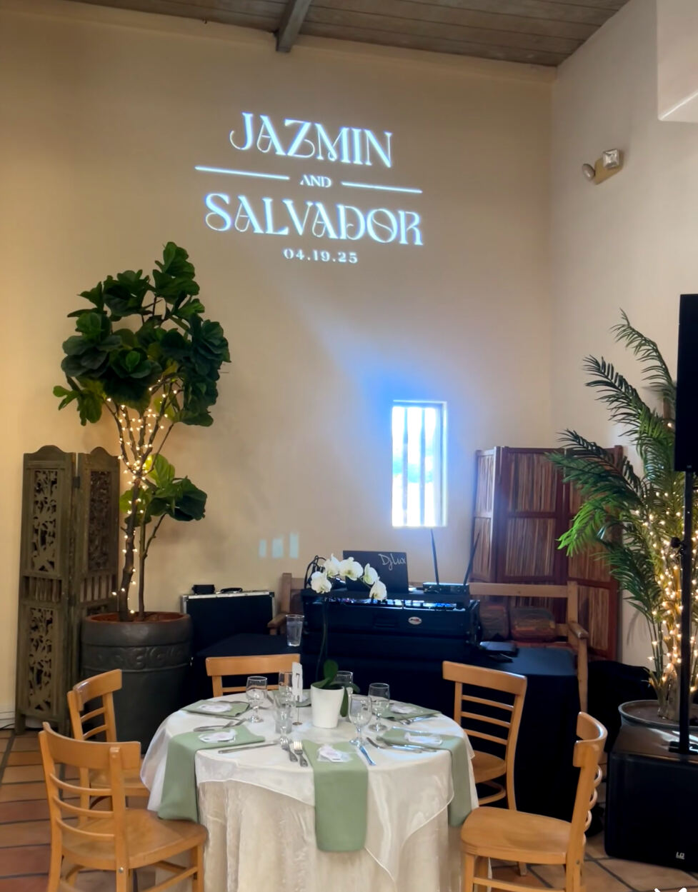 Jazmin and Salvador's names projected above their reception table, dated 04.19.25