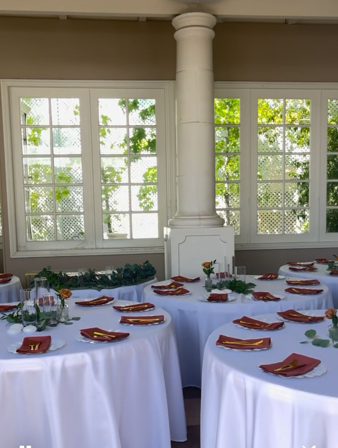 Round reception tables set with white linens and eucalyptus garland